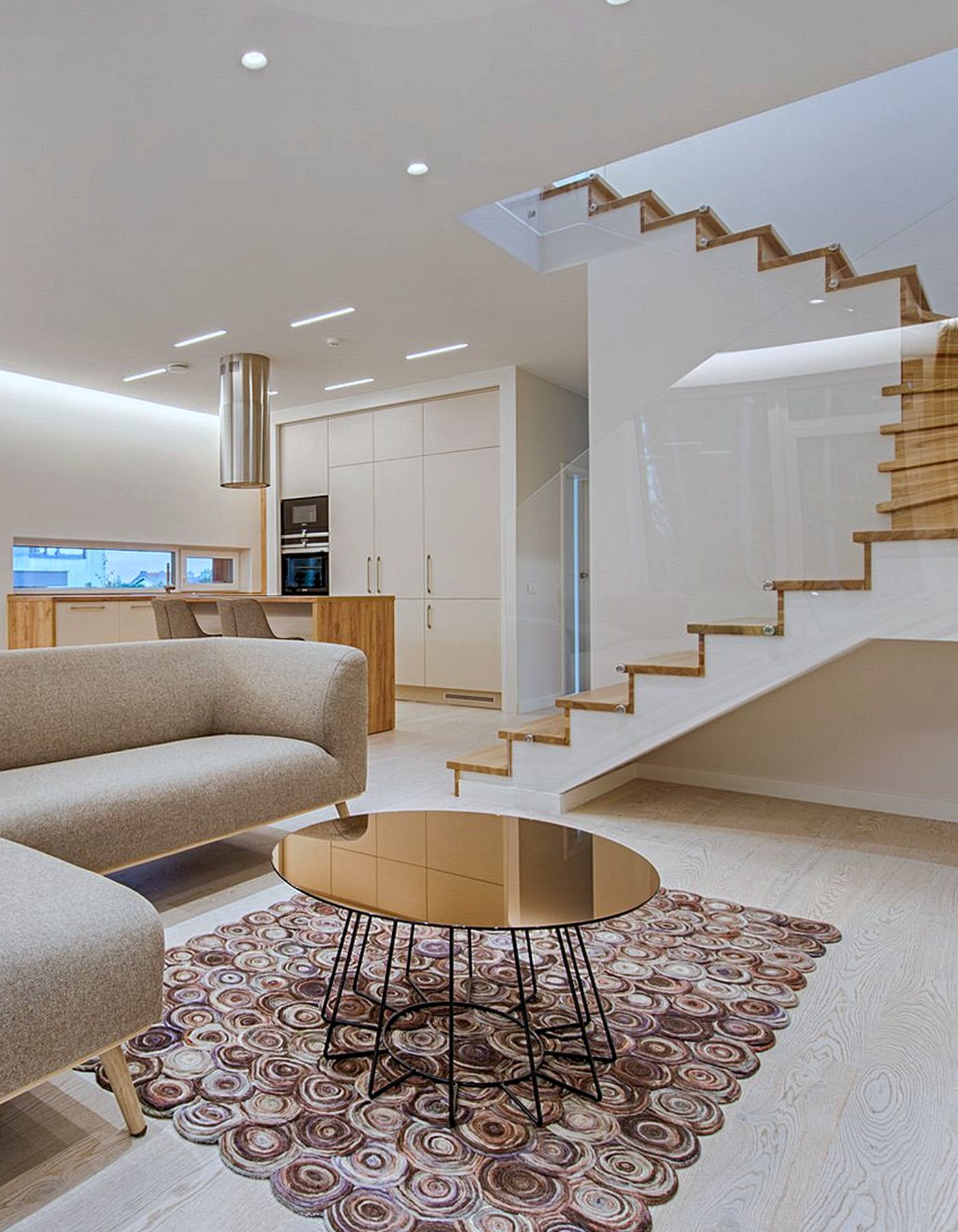 Clean open-plan home with a glass staircase, kitchen and living area