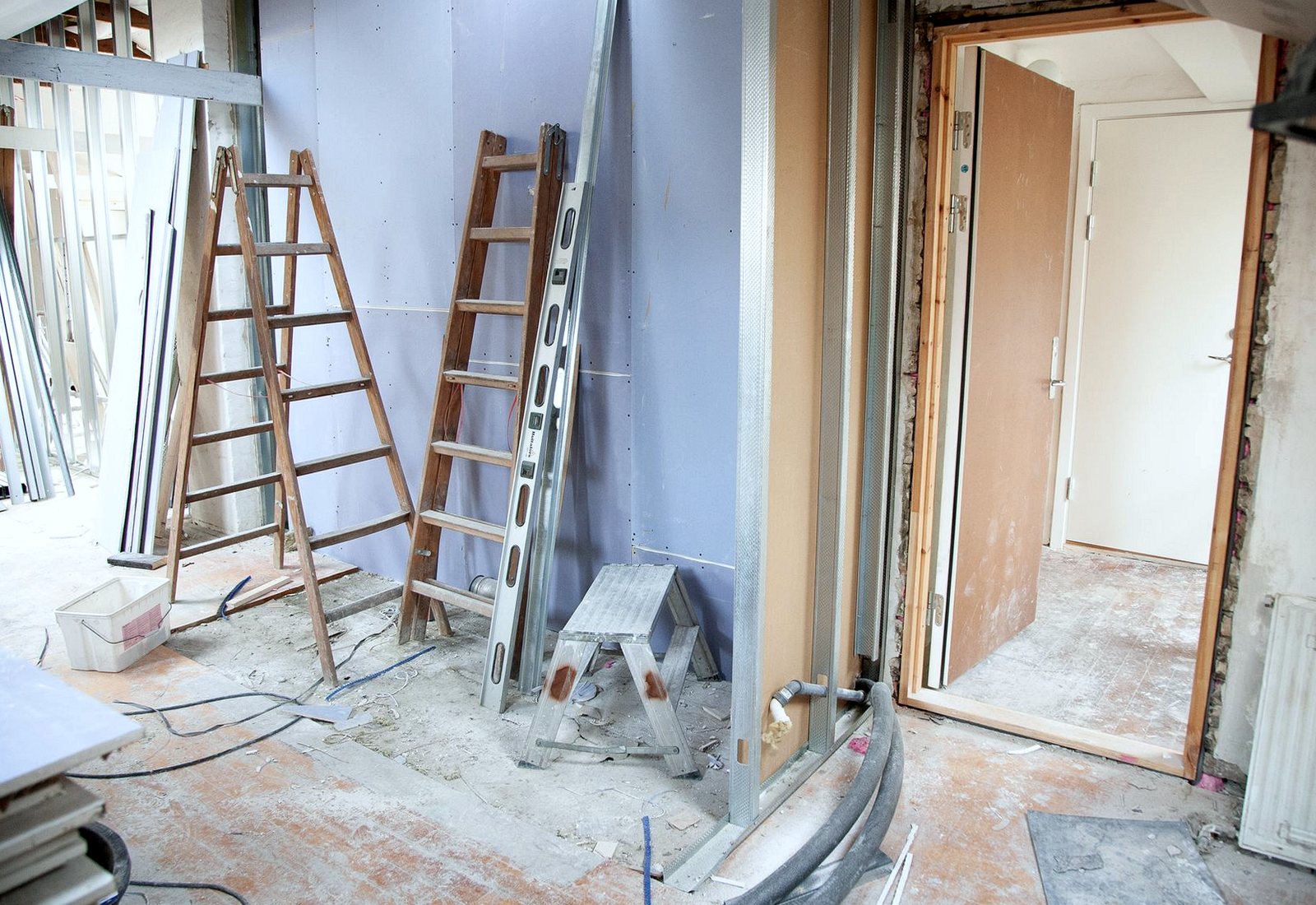 Unfinished interior with plasterboard, ladders, dust and building debris