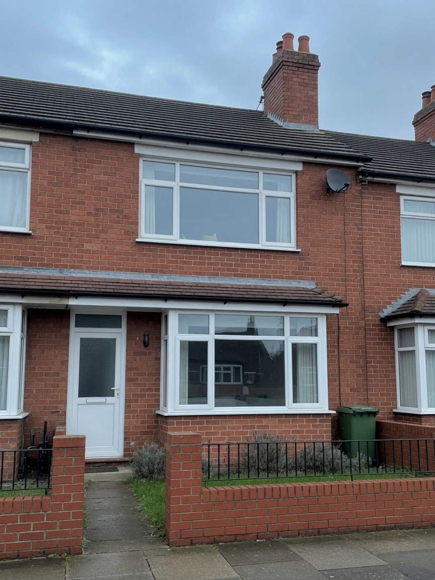 Red-brick UK terrace house with white uPVC windows